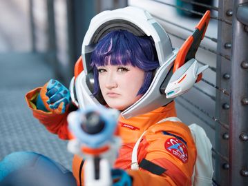 Person in futuristic astronaut costume aiming a weapon.