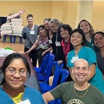 A group of smiling people in a room with stacked towels.