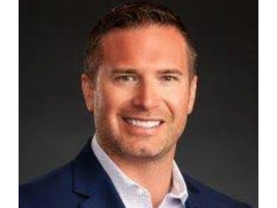 Professional headshot of a smiling man in a blue suit jacket.