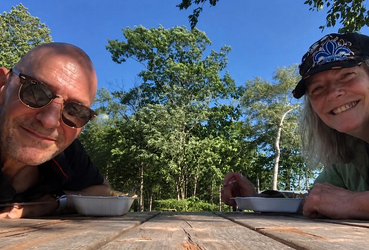 Two people enjoying a meal outdoors on a sunny day.