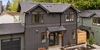 Modern gray two-story house with large windows and a small porch.