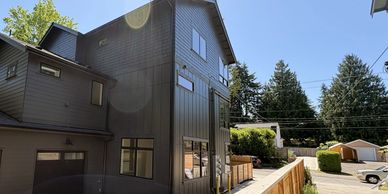 Modern dark-colored house with large windows and a clear blue sky.