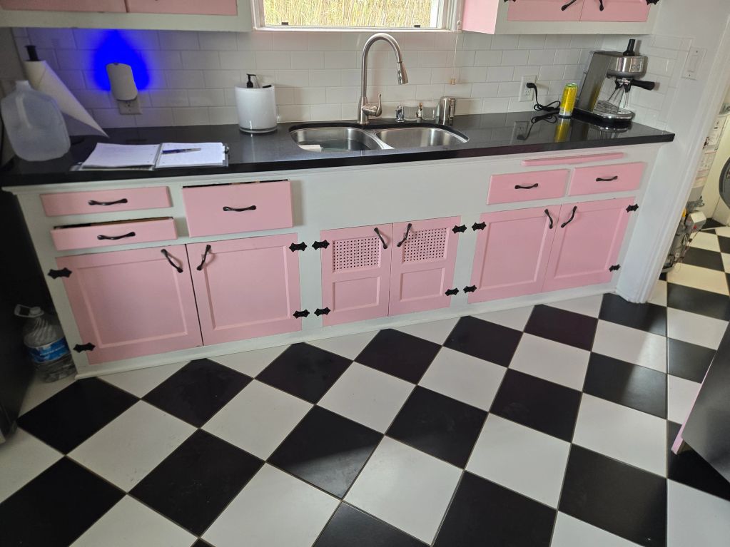 Kitchen with pink cabinets and black-and-white checkered floor.