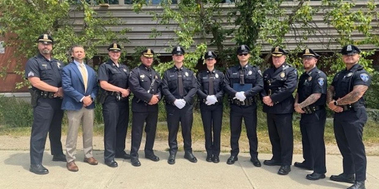Group of police officers and a man in a suit posing outdoors.