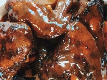 Grilled chicken wings generously coated in a rich, glossy barbecue sauce.