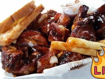 Barbecue ribs with fries and Texas toast, topped with sauce.