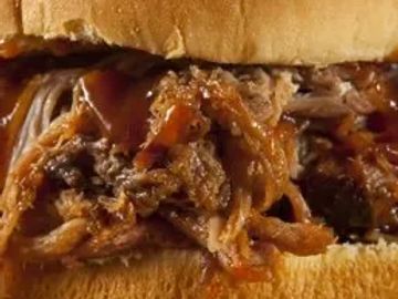 Close-up of a pulled pork sandwich with barbecue sauce.