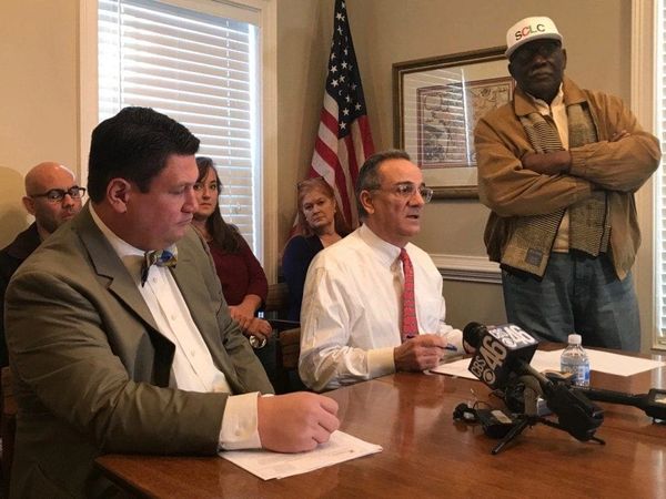 A group of people at a press conference with microphones on a table.