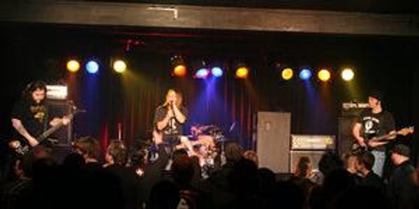 Rock band performing live on stage with colorful lights and audience.