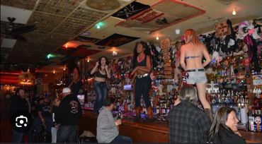 Women dancing on a bar counter in a lively pub.
