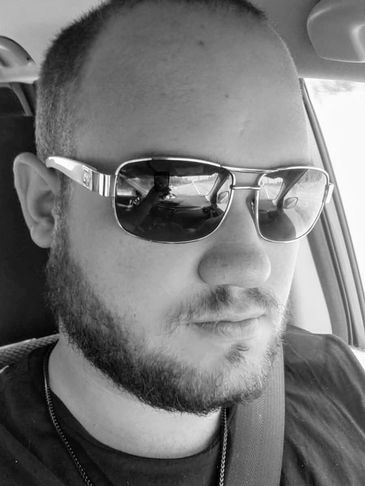 Strong man wearing Shades while driving. Tree of life necklace