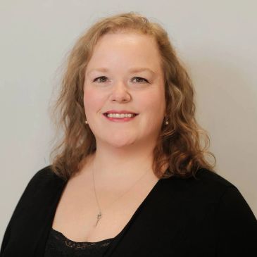 Smiling woman with curly blonde hair and black top.