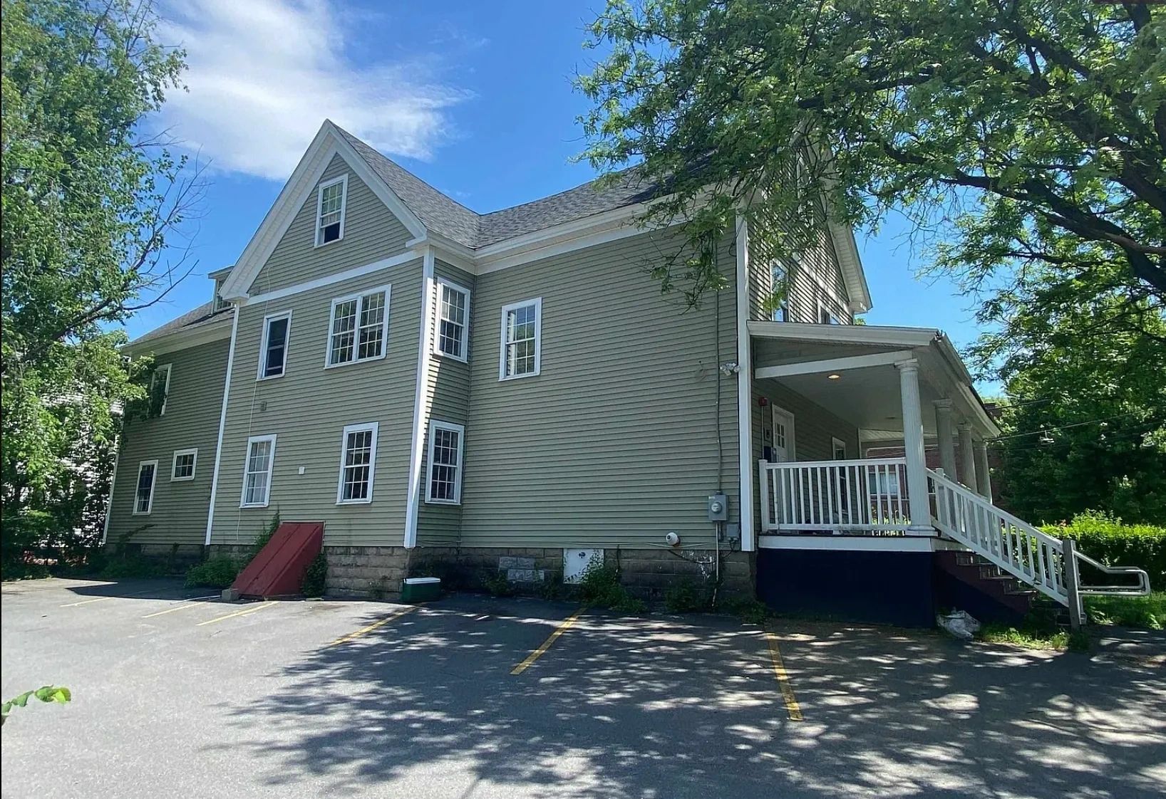 Large two-story house with gray siding and white trim under a blue sky.