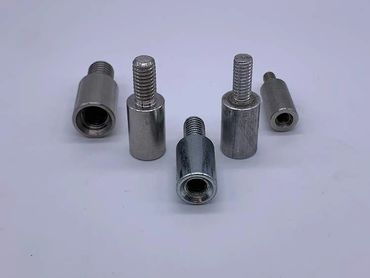 Various metal threaded inserts and bolts arranged on a white surface.