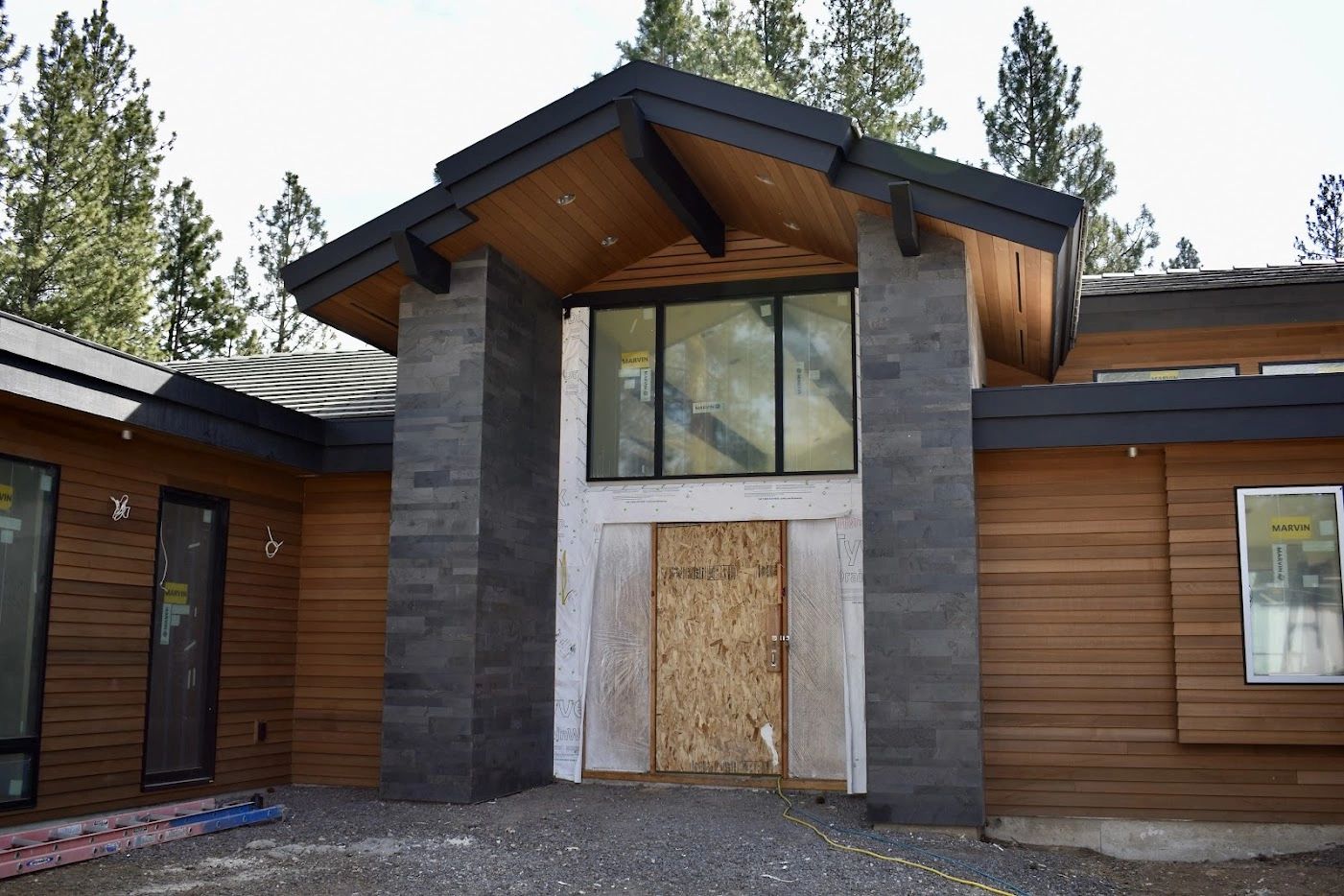 Cedar siding, stone and timber entry on a mountain style custom home, the style Elite Construction Contracting builds in Sisters and Bend, Oregon