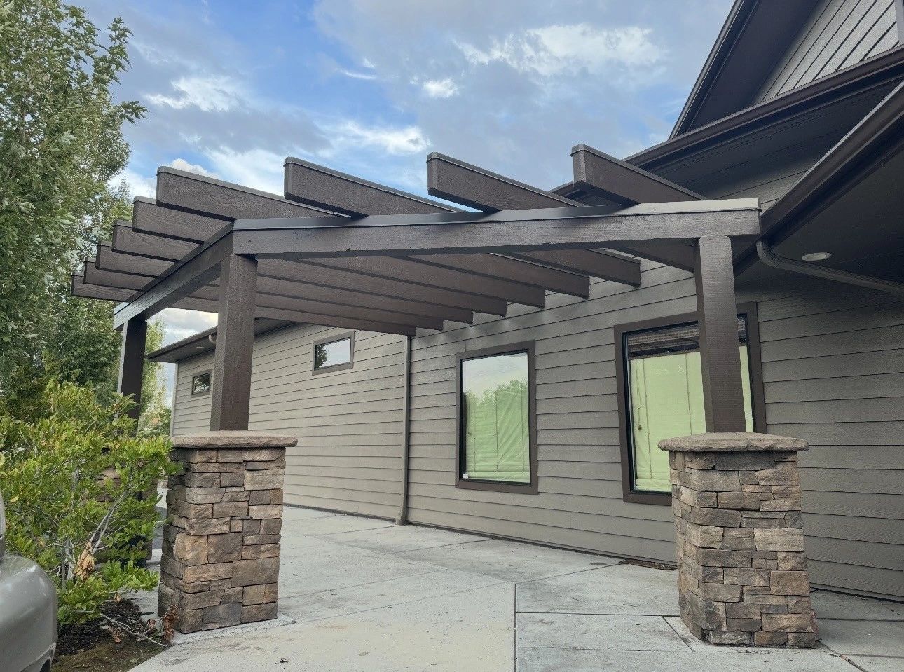 Custom pergola with heavy timber beams and stone columns on a patio in Bend, Oregon built by Elite Construction Contracting