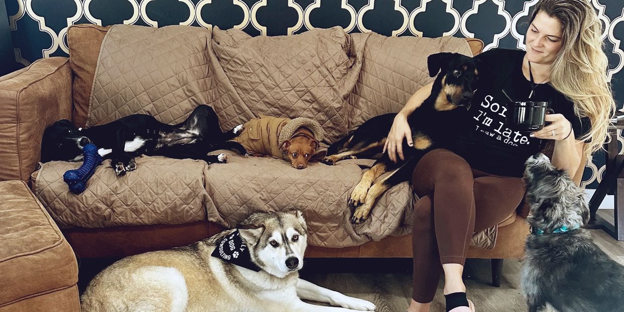 Canine Behaviorist Ashley Valentine sitting on couch enjoying her morning coffee with 5 dogs 