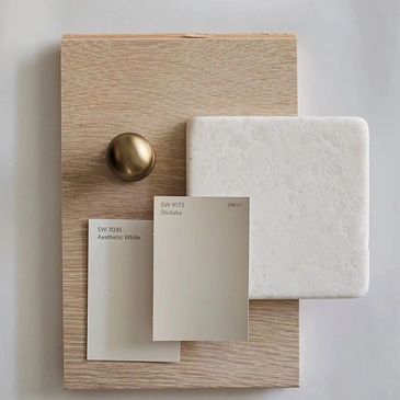 Neutral color palette with wood, brass, and paint samples for interior design.