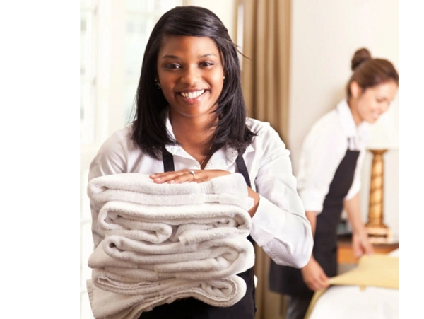 Smiling woman holding a stack of towels.