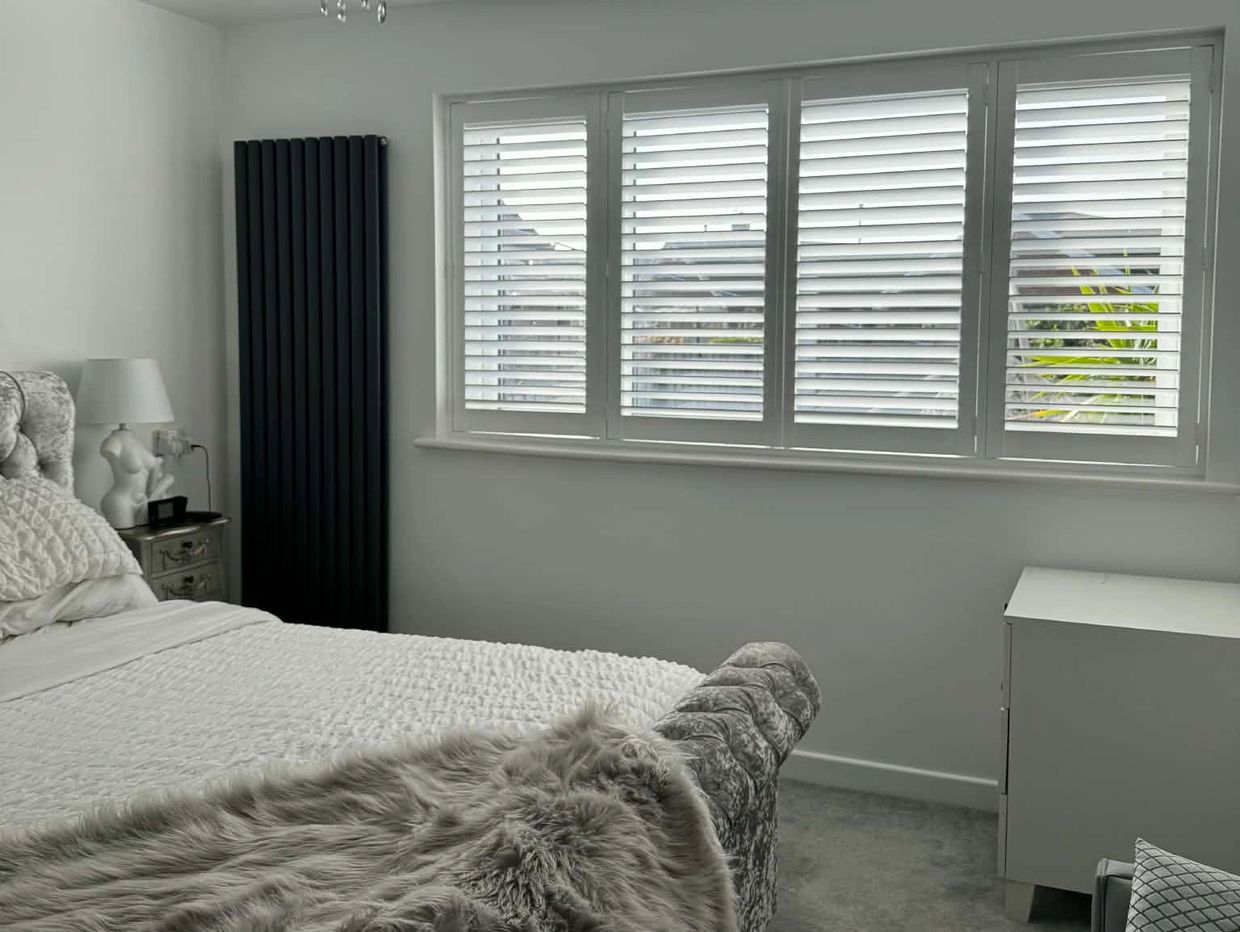 Minimalist bedroom with a bed, window blinds, and a radiator.