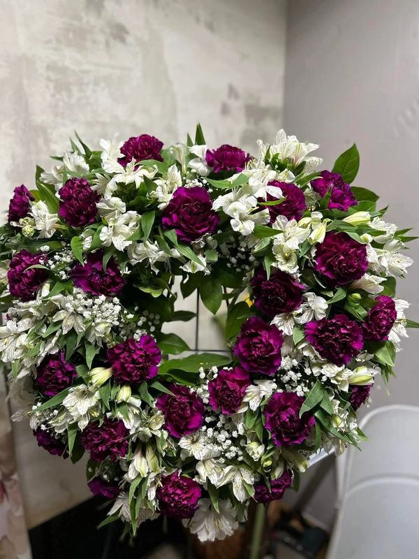 Heart-shaped wreath with purple and white flowers and green leaves.