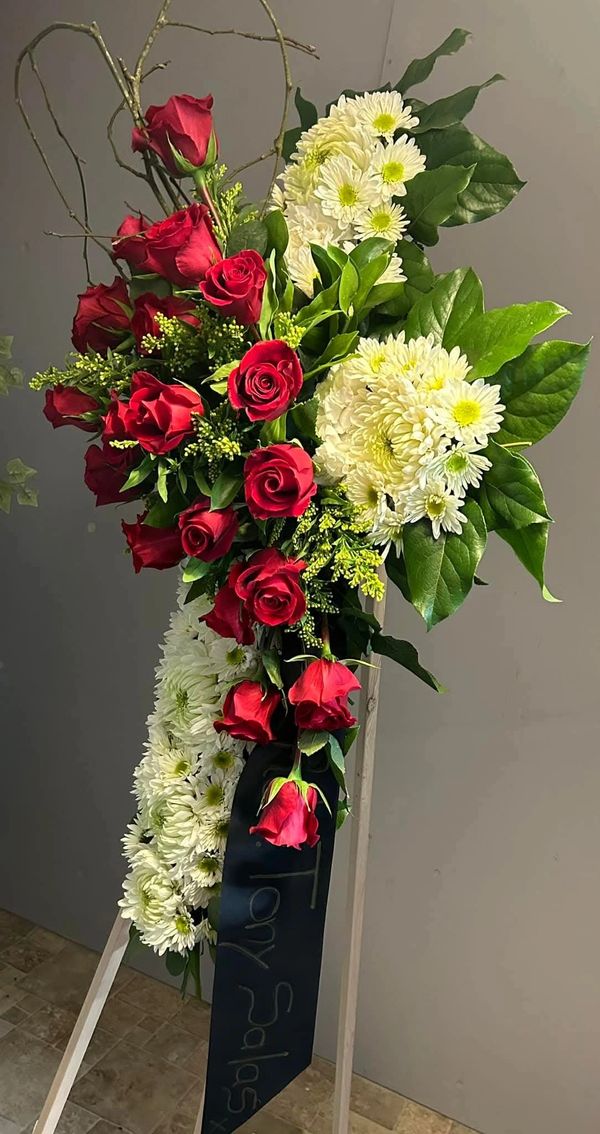 Elegant funeral flower arrangement with red roses and white chrysanthemums.