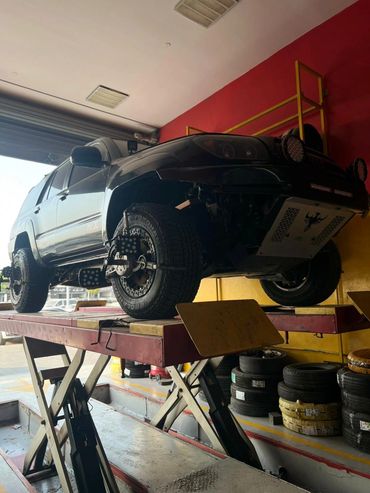 SUV on a hydraulic lift with wheel alignment sensors in a garage.