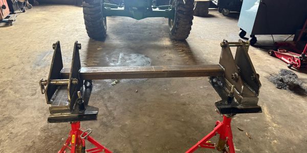 Metal frame held by two red jack stands in a workshop.