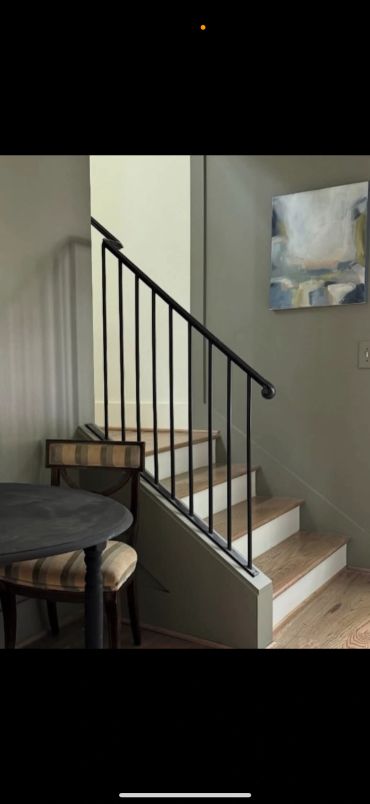 Wooden staircase with black railing and a small round table.