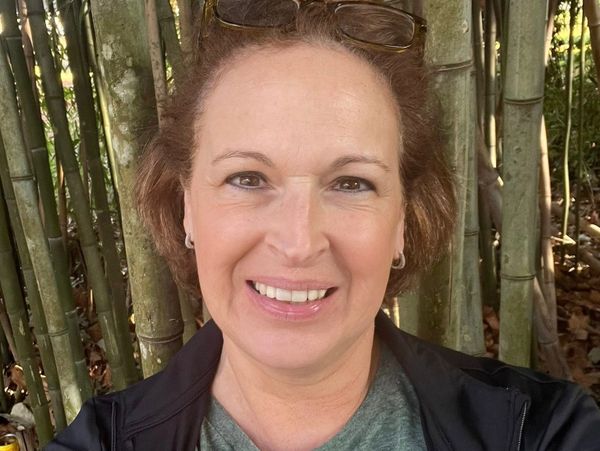 Smiling woman outdoors with bamboo background.