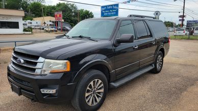 Black Ford SUV parked in a lot near a car dealership.