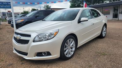 White Chevrolet Malibu sedan parked at a dealership lot.