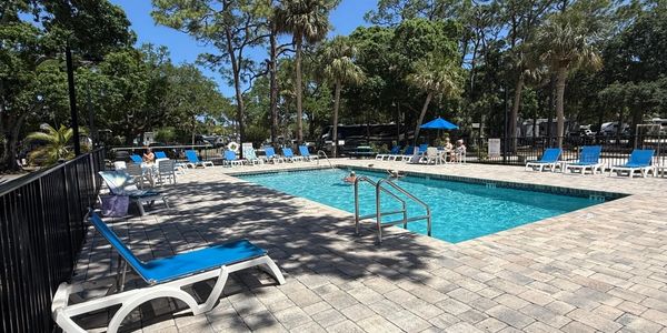 Outdoor swimming pool with lounge chairs and trees.
