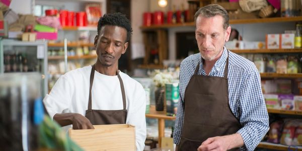 Two men wearing aprons working together in a store.