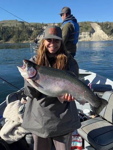 Woman proudly holding a large fish on a boat during a fishing trip.