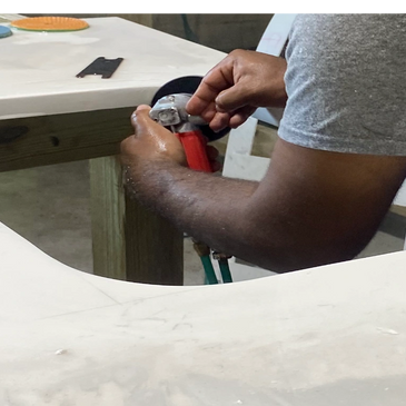 Person polishing or grinding a cutout in a marble or stone countertop.