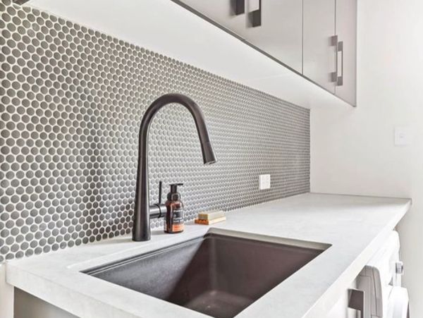 Modern kitchen sink with gray backsplash and matte black faucet.