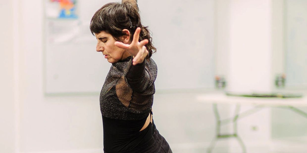 A focused dancer extends her arm in a graceful pose during practice.