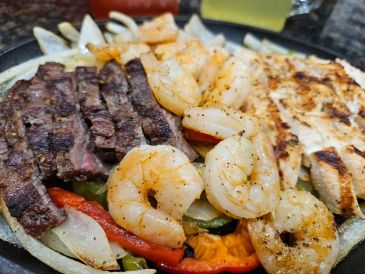 Grilled steak, shrimp, and chicken with vegetables.