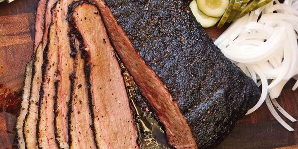 Sliced smoked brisket with pickles and onions.