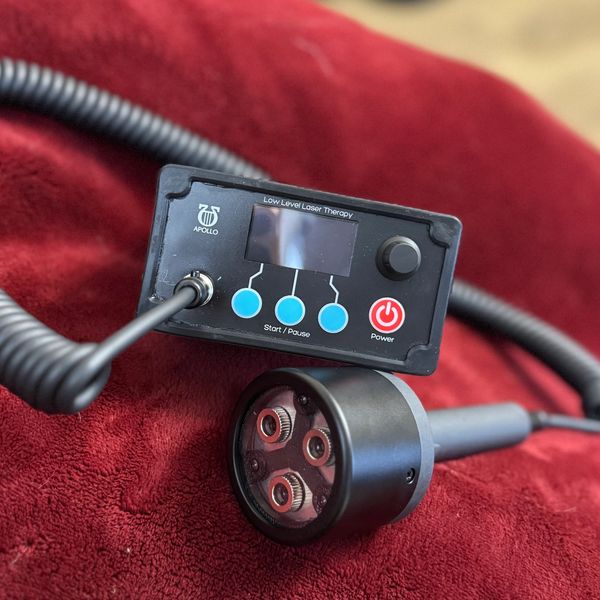 Close-up of a low level laser therapy device with control panel and laser head.