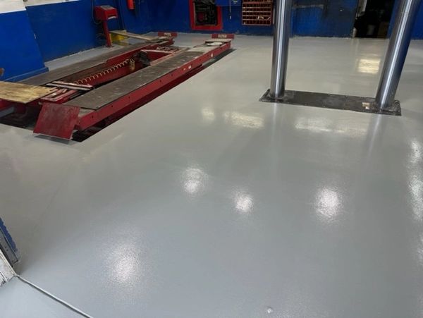 Newly coated smooth gray floor in an automotive workshop.