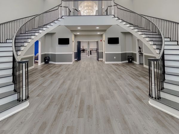 Spacious lobby with dual curved staircases and modern flooring.