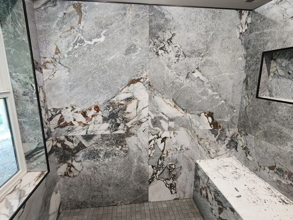 Elegant bathroom with marble walls and a bench.