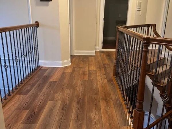 Wooden floor hallway with metal and wood railings on stairs.