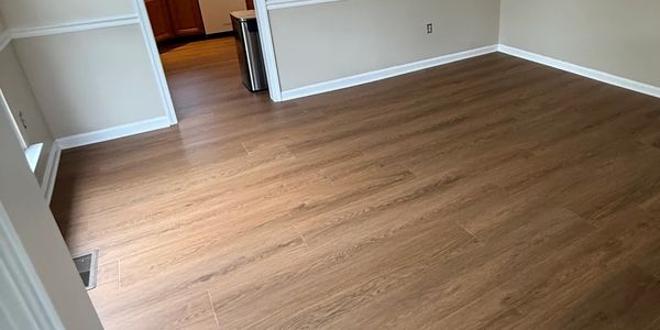 Empty room with new wood flooring and beige walls.
