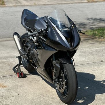 Sleek black sports motorcycle parked outdoors on concrete.