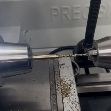 Close-up of a metal drill bit in a precision lathe machine with metal shavings.