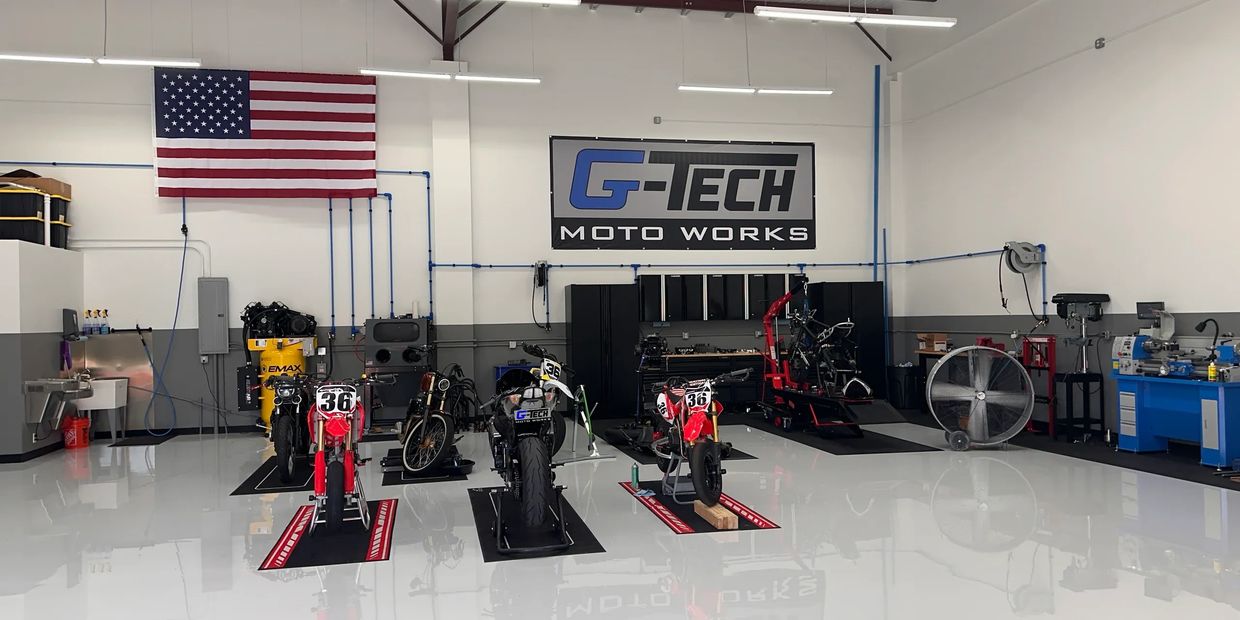 Clean motorcycle workshop with several bikes and an American flag.