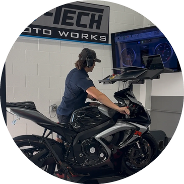 Person on a motorcycle using a simulator setup with screens displaying speedometers.